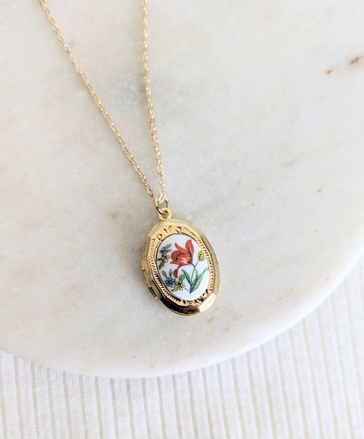 This small and dainty little gold plated locket features a sweet red-orange tulip flower vintage glass cabochon. It opens with the hinge at the side and there is space inside for a photo, secret message or little hand stamped initial. Suspended from either a gold plated chain with lobster clasp or a 14k gold filled chain with spring clasp close. Personalise for the perfect gift with a little hand stamped tag (fits one single Initial) https://etsy.me/33z0KEa or a Crystal birthstone: https://etsy.me/2HxFczT Add a Hand Stamped Initial Inside (pic 5) https://etsy.me/3BPkx0b Handmade with LOVE in Australia 🐨 | ADDITIONAL INFORMATION | Gold filled jewellery is an affordable alternative to solid gold that is durable, tarnish resistant and wearable for people with sensitive skin. Please allow 1-4 Cute Etsy Jewelry, Gifts To Give To Your Best Friend, Flower Locket Necklace, Little Women Gifts, Simple Gold Jewelry Aesthetic, Gold Stacked Necklaces, Cottage Core Accessories, Vintage Jewelry Aesthetic, Cute Accessories Aesthetic