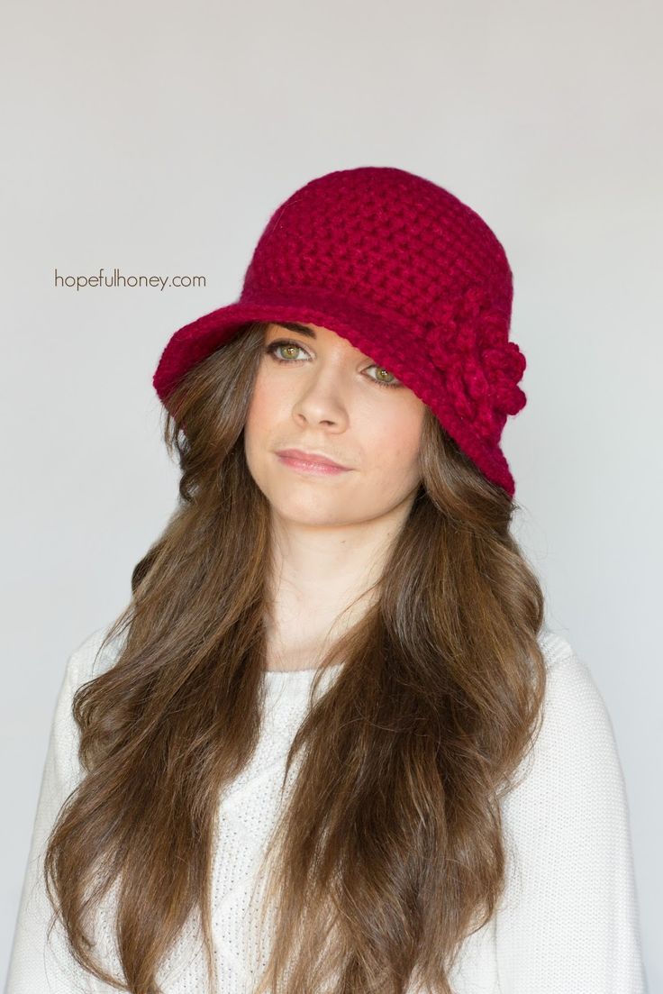 a woman wearing a red crochet hat with long hair in front of a white background