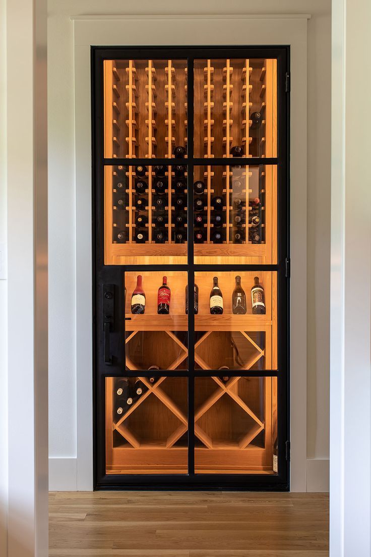 a wine cellar with many bottles in it and lights on the wall behind it, along with hardwood flooring