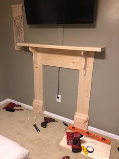 a tv mounted above a fireplace in a room with construction tools on the floor next to it