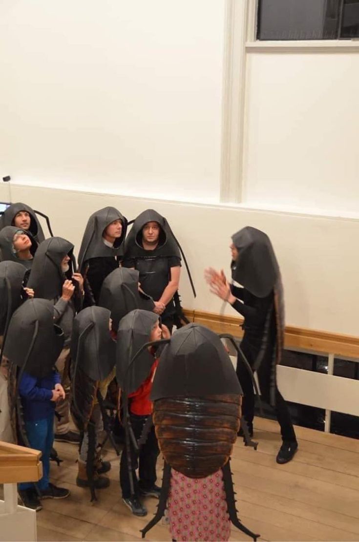 a group of people in black hoods standing next to each other on a wooden floor