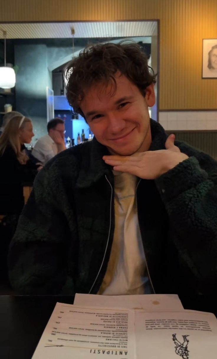 a man sitting at a table with a menu in front of him and smiling for the camera