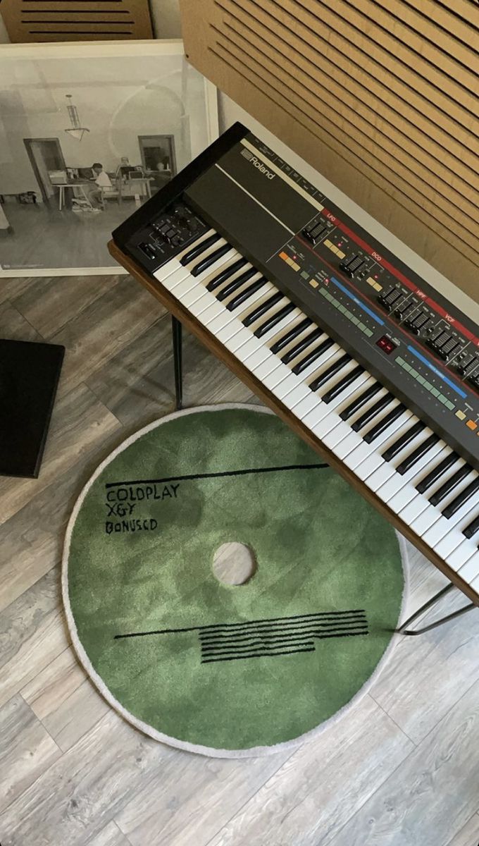 an electronic keyboard sitting on top of a hard wood floor next to a record player