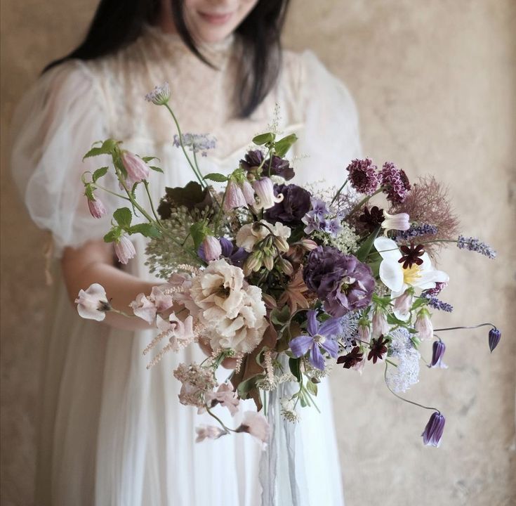 a woman holding a bouquet of flowers in her hands