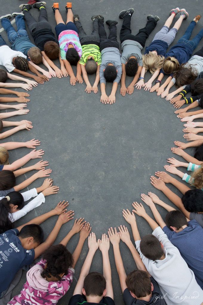 a group of children standing in a circle with their hands together to form the shape of a heart