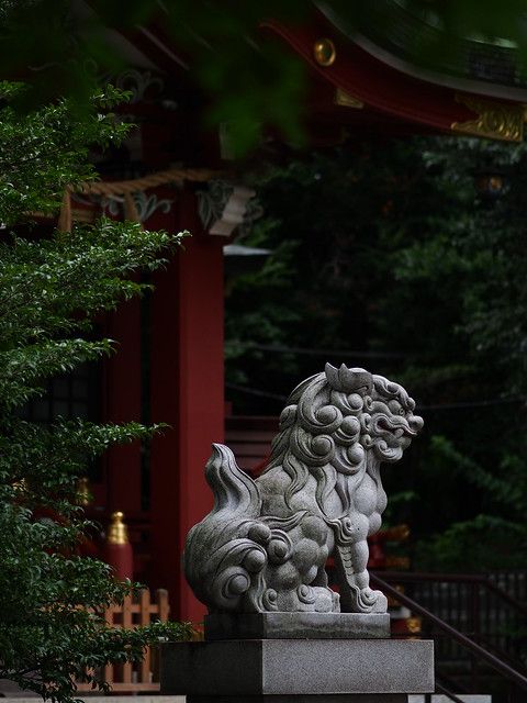 a stone lion statue in front of a red building