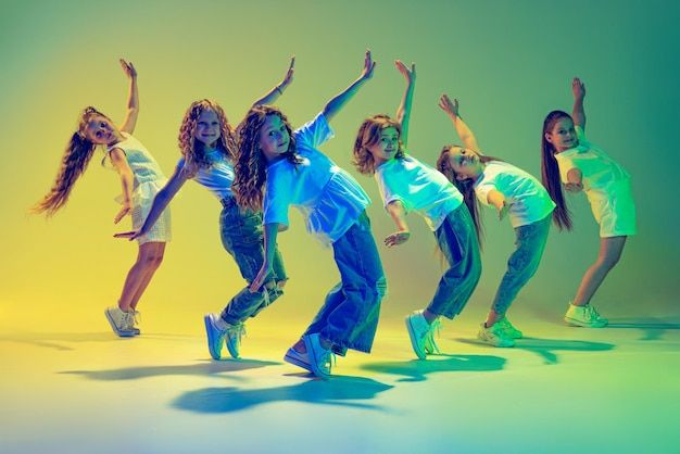 a group of young women dancing together in front of a yellow and green background with their arms up