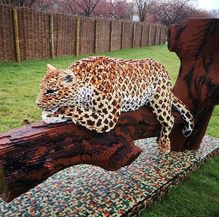 an animal made out of legos sitting on top of a bench in the grass