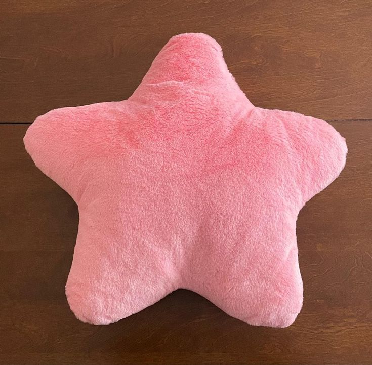 a pink star shaped pillow sitting on top of a wooden floor