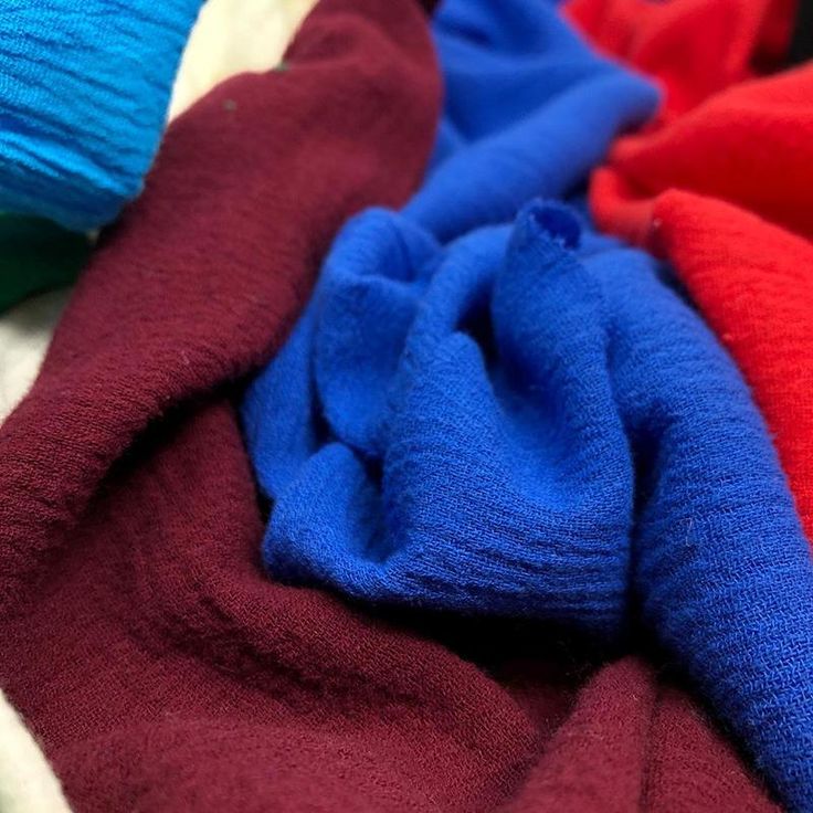 several different colors of clothing laying on top of each other in close up view, including red, white and blue