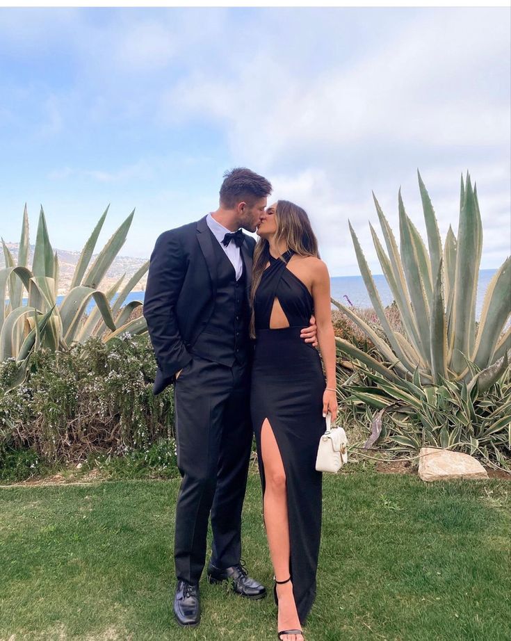 a man in a tuxedo kisses a woman's cheek on the grass