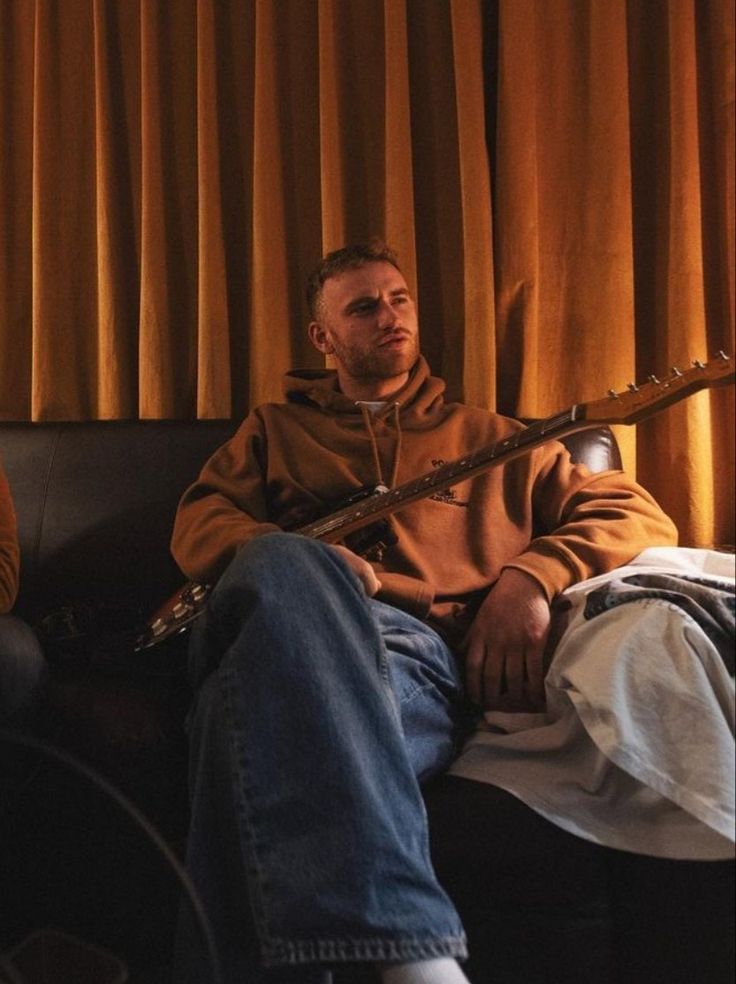 a man sitting on top of a couch next to a window holding a wooden stick