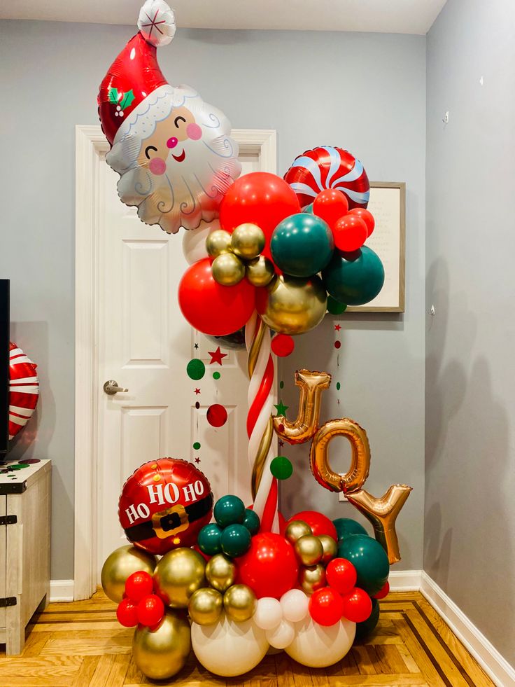 a bunch of balloons that are sitting on the floor in front of a door with santa clause