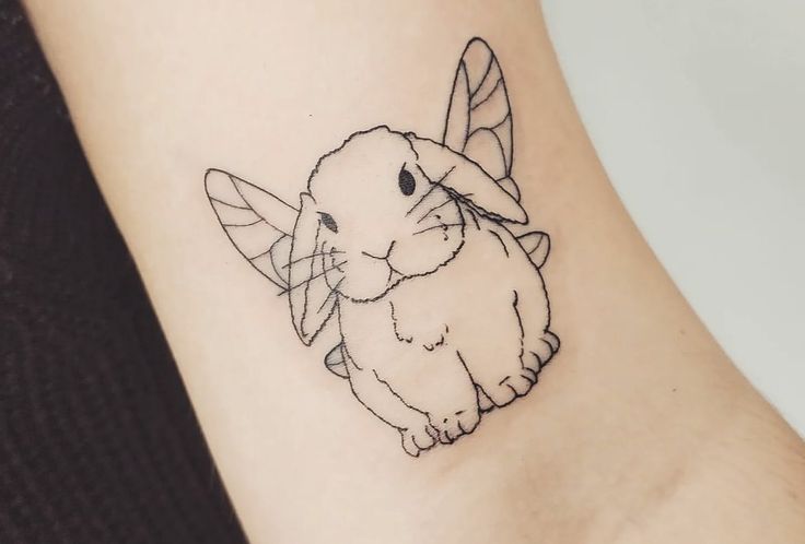 a small rabbit tattoo on the ankle with a bee around it's neck and ears