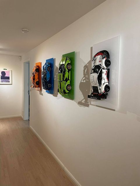 a long hallway with three paintings on the wall and two cars mounted to the wall