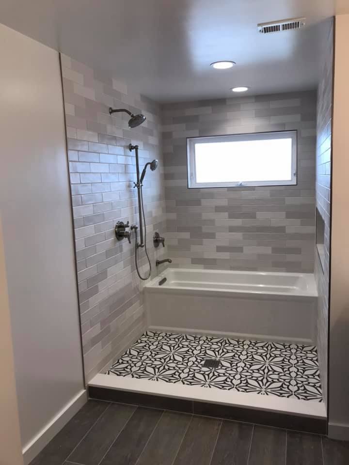 a bathroom with tile flooring and a bathtub in the corner, next to a window