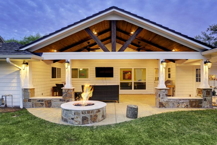 a house with a fire pit in the front yard and covered patio area next to it