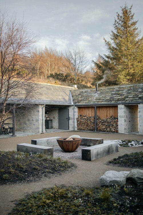 an outdoor courtyard with stone walls and trees in the background, surrounded by gravel blocks