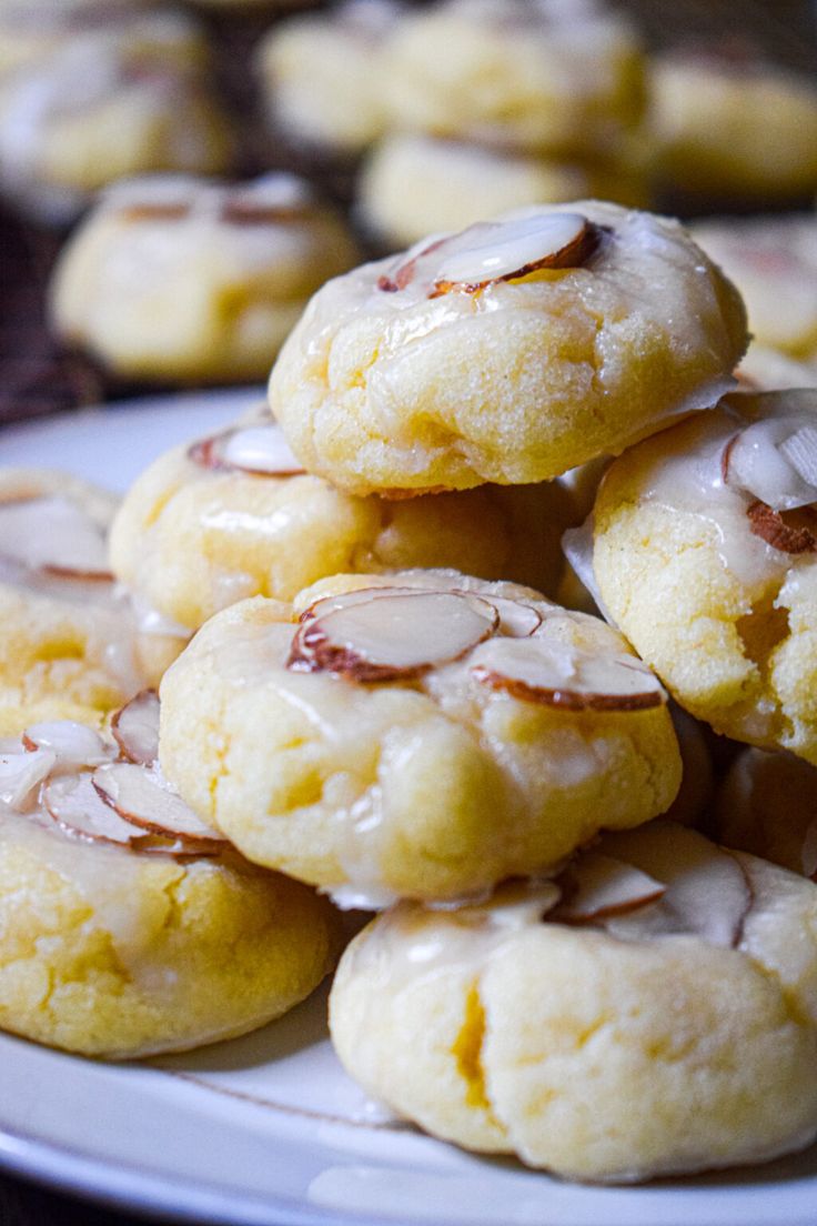 a plate full of cookies with almonds on top and drizzled in icing