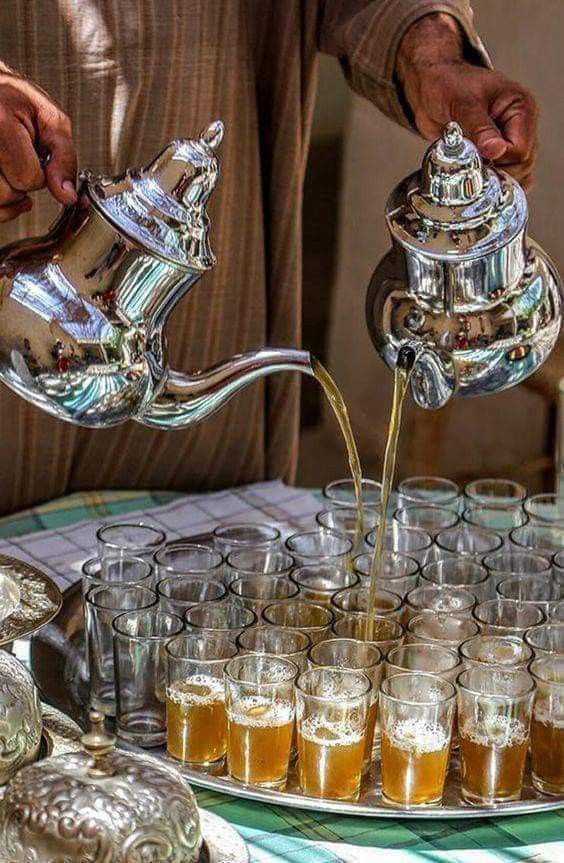 a person pouring tea into glasses on a tray