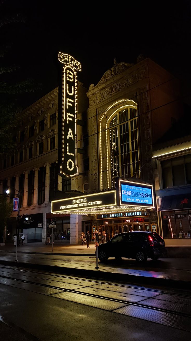 a car driving down the street in front of a theater