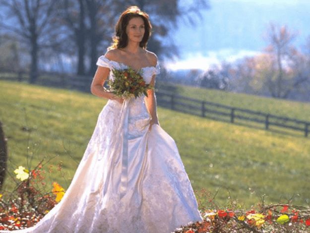 a woman in a white wedding dress is posing for the camera with flowers on her bouquet