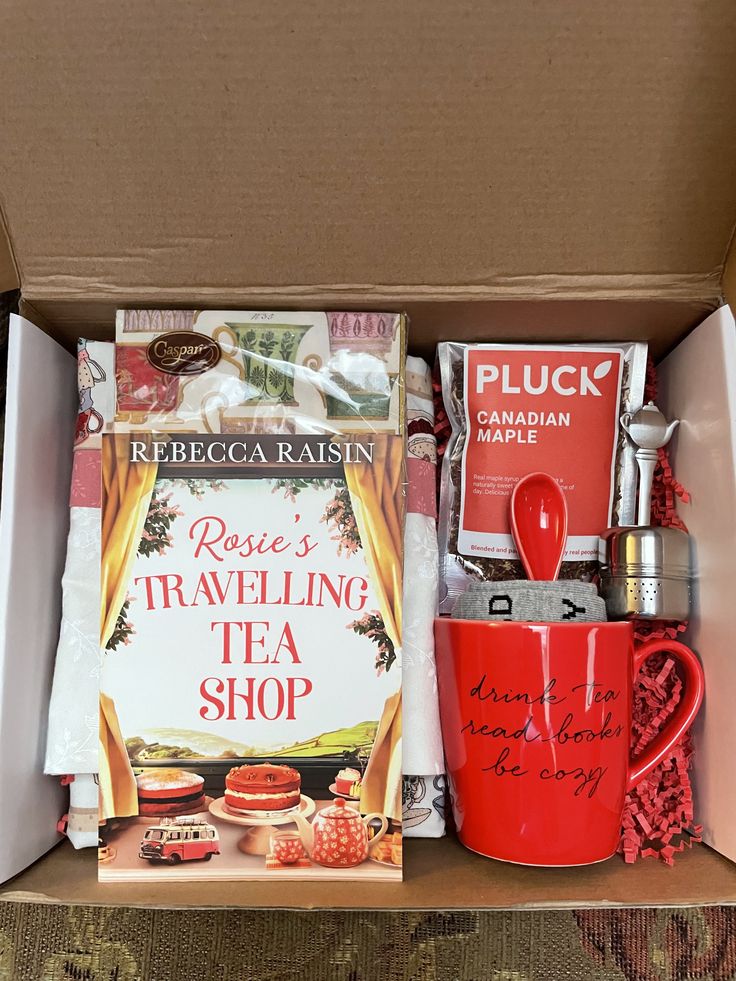 an open box containing tea, books and coffee mugs with writing on the inside