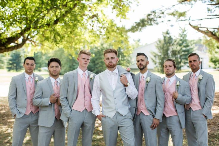 a group of men standing next to each other in front of a lush green tree