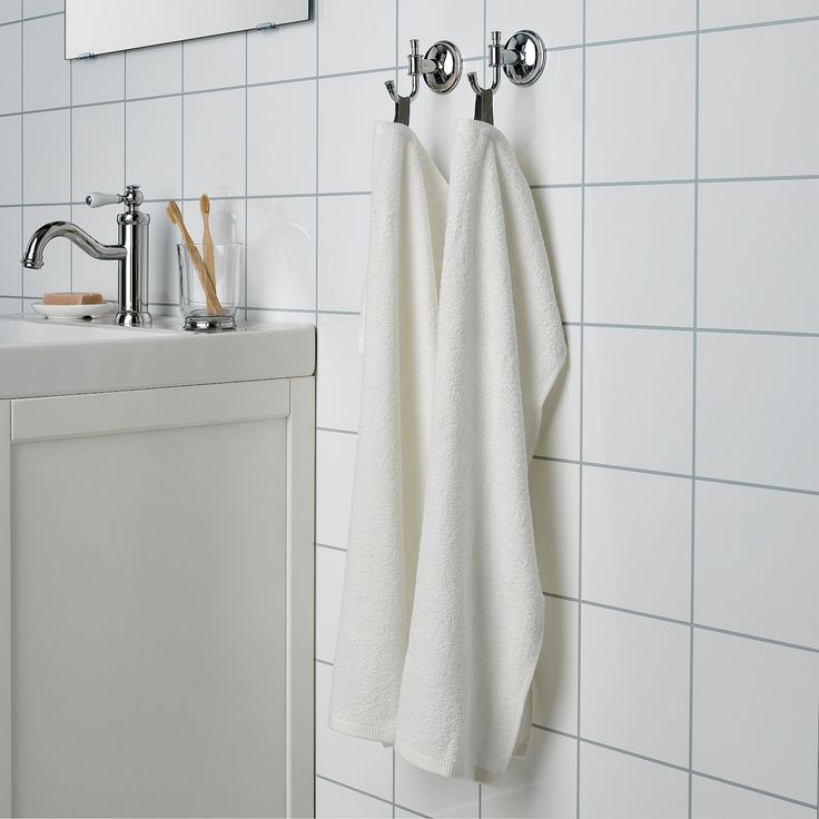 a white towel hanging on the wall next to a sink with two faucets