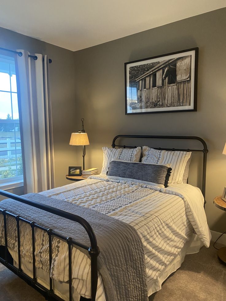 a bed sitting in a bedroom next to two lamps on either side of a window