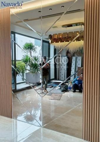 a man standing in front of a large mirror on the wall next to a plant