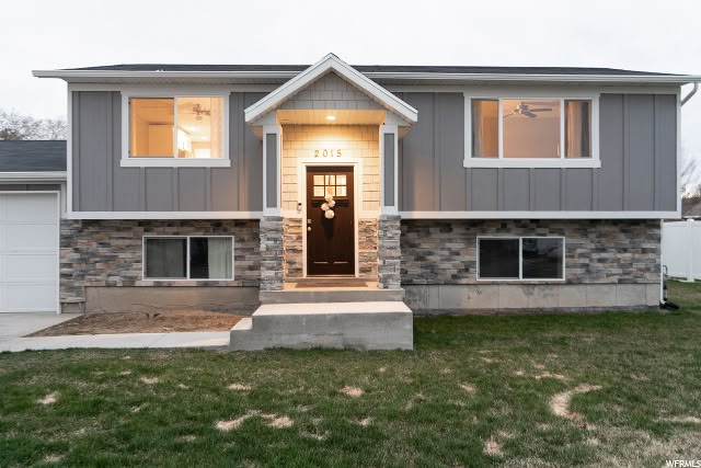 a house that is in the grass with some lights on and two garages behind it