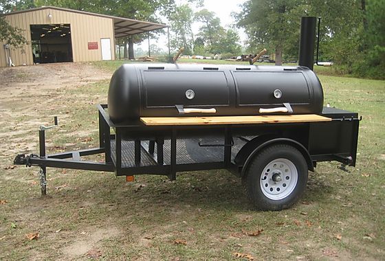 a large black bbq sitting on top of a grass covered field