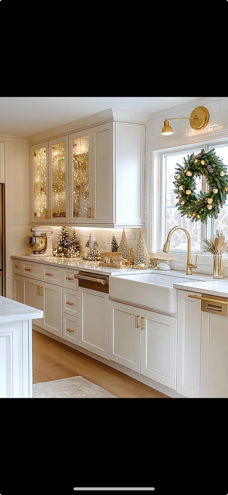 a kitchen decorated for christmas with wreaths on the window sill and white cabinets