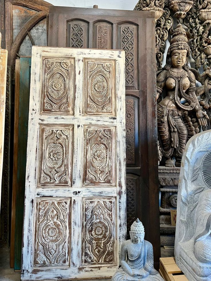 an old wooden door sitting next to a buddha statue and other antique items in a room