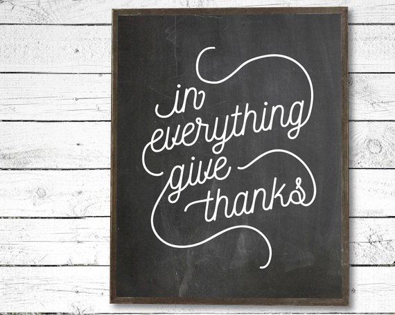 a chalkboard with the words in everything give thanks written on it against a white wooden background