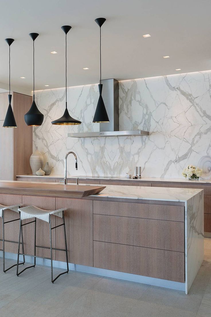 a modern kitchen with marble counter tops and pendant lights hanging from the ceiling over the island