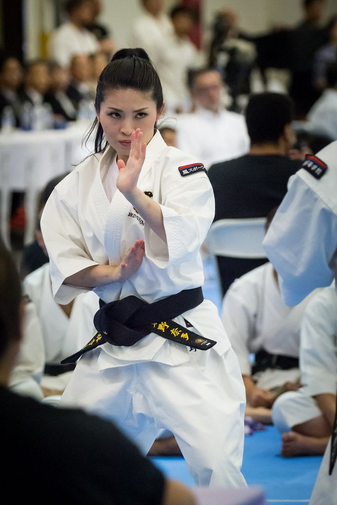 a woman is doing karate in front of other people