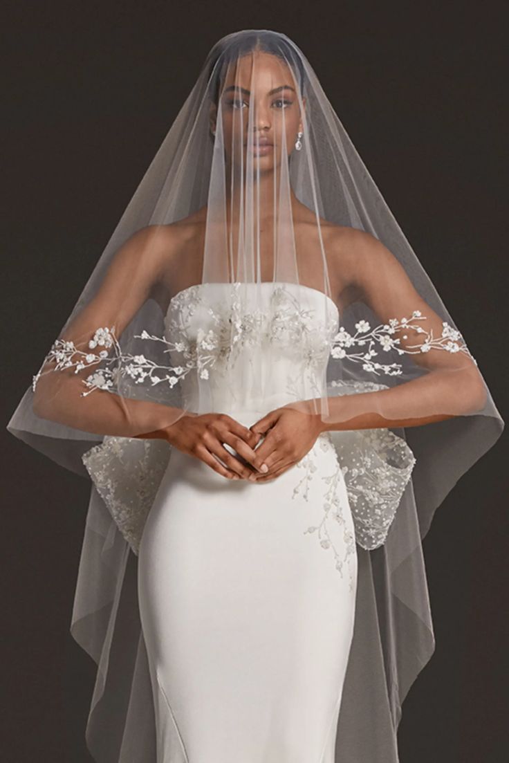 a woman in a white wedding dress with a veil over her head and flowers on it