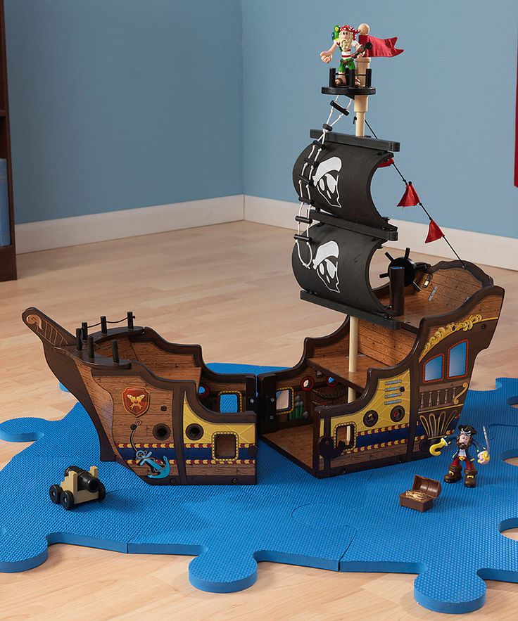 a wooden pirate ship playset in a child's room with blue rugs