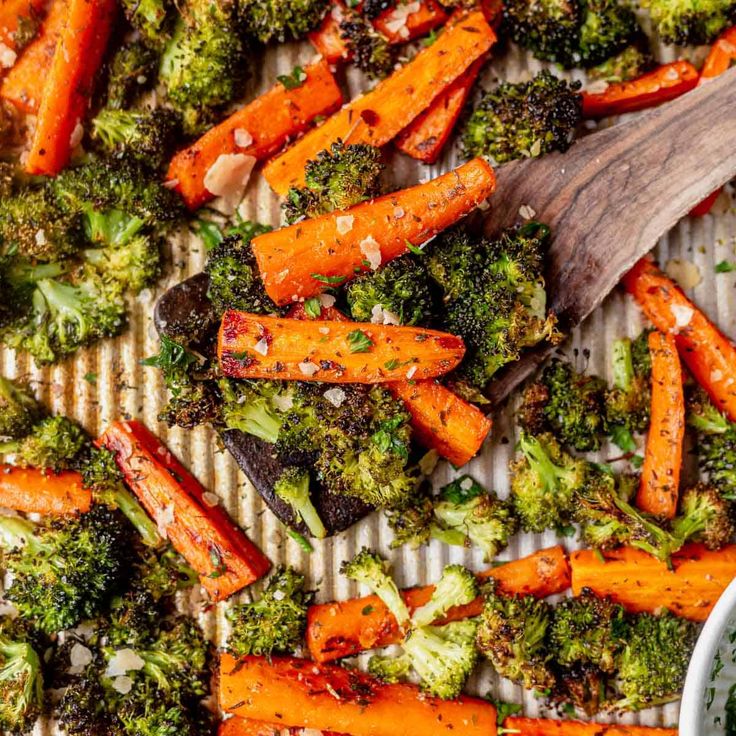 broccoli and carrots on a tray with a wooden spoon next to them