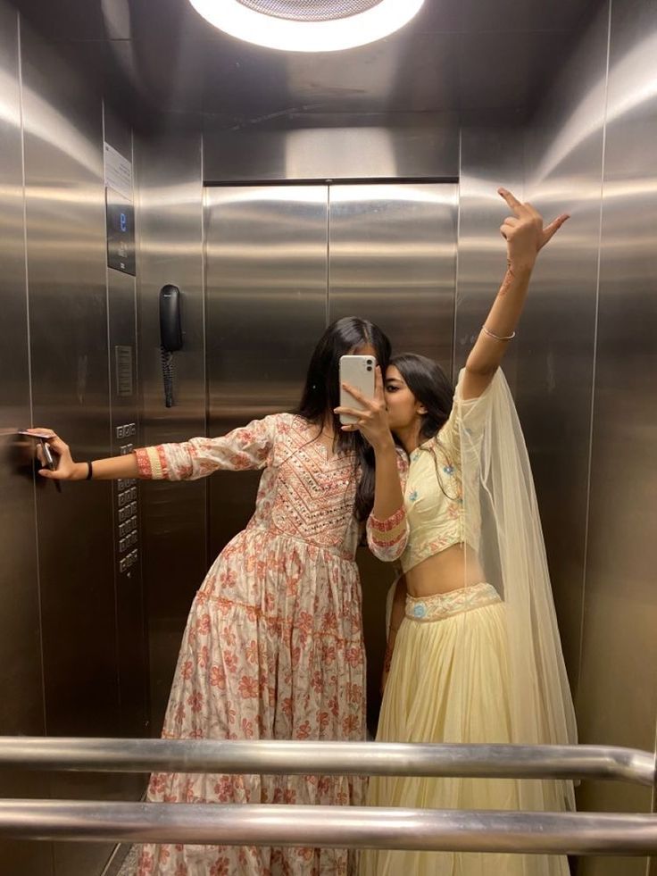 two women taking pictures in an elevator