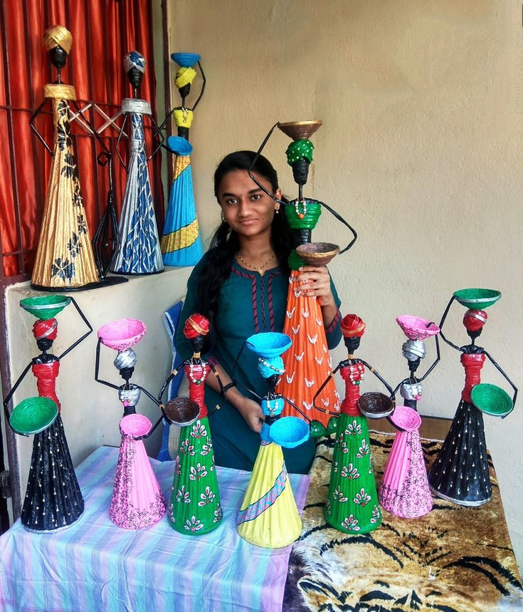 a woman standing next to a table filled with vases and other decorative items on it