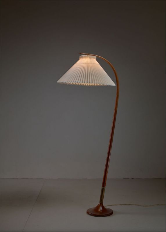 a floor lamp with a white shade on it's side and a wooden base