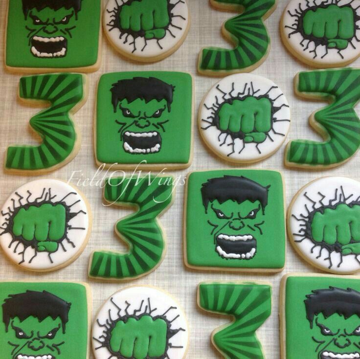 decorated cookies with green and black designs depicting the faces of superheros, including hulk