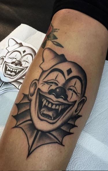 a close up of a person's arm with a tattoo on it and an evil clown