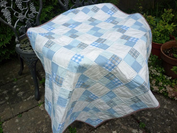 a blue and white checkered blanket sitting on top of a bench next to potted plants