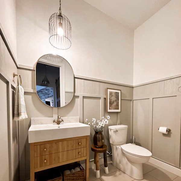 a white toilet sitting next to a sink in a bathroom under a round light fixture