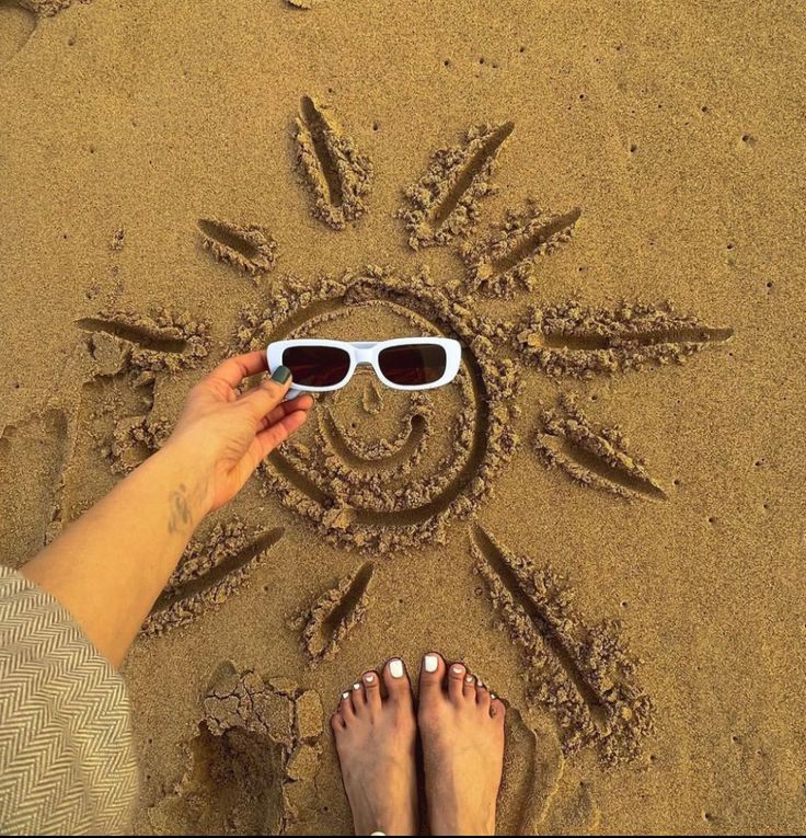 a person wearing sunglasses standing in the sand