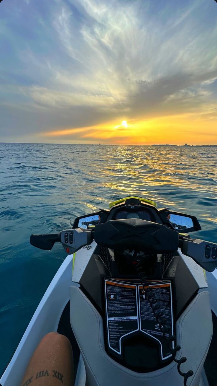 the sun is setting over the ocean as seen from a motorboat in the water